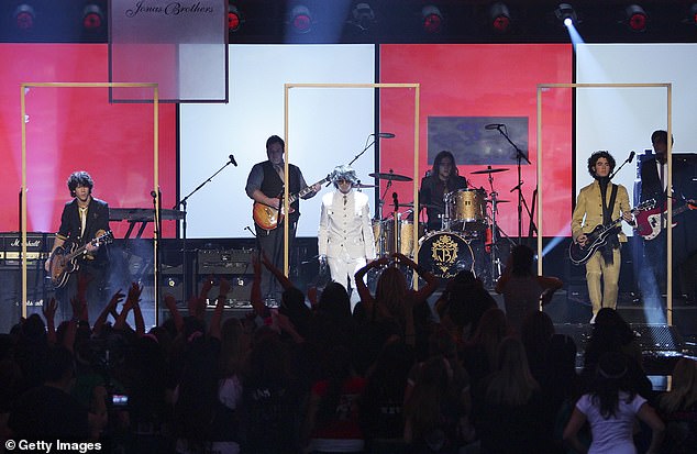 2007 American Music Awards: во время выступления Jonas Brothers на церемонии вручения наград American Music Awards 2007 Джо (в центре) пытался пройти через разбитую стеклянную дверь во время постановки сцены со своими братьями, но его нога застряла, и он упал на землю. его колени на разбитом стекле, момент, который транслировался по национальному телевидению