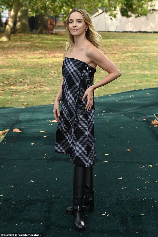 Красота: Джоди Комер продемонстрировала свой смелый стиль в черном платье в клетку без бретелек в сочетании с кожаными сапогами до колена.