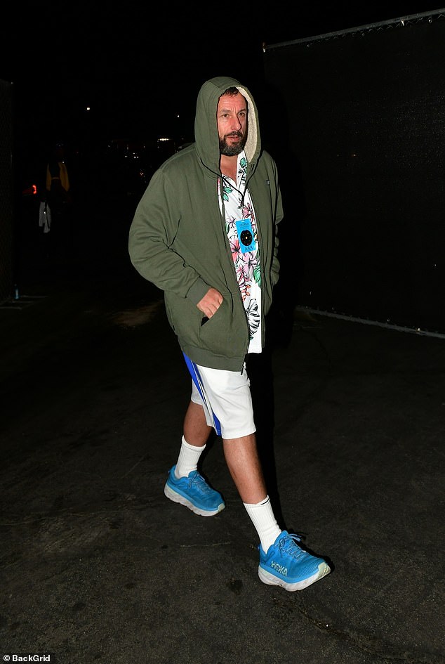 Адам Сэндлер надел оливково-зеленую куртку с капюшоном поверх гавайской рубашки, спортивные шорты и синие кроссовки.