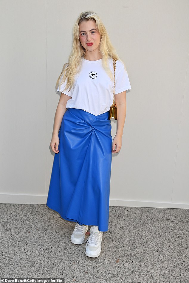 Ярко в синем: 23-летняя Анаис Галлахер, дочь культового персонажа Oasis Ноэля, выбрала смелую кожаную юбку-миди с белой футболкой, а обесцвеченные локоны она уложила длинными волнами.