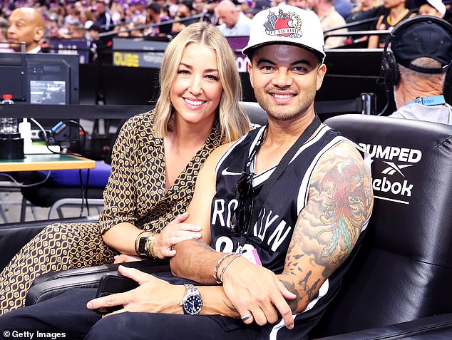 Тем временем Гай надел черную майку с белыми надписями, а также черные брюки и белую кепку с рисунком.