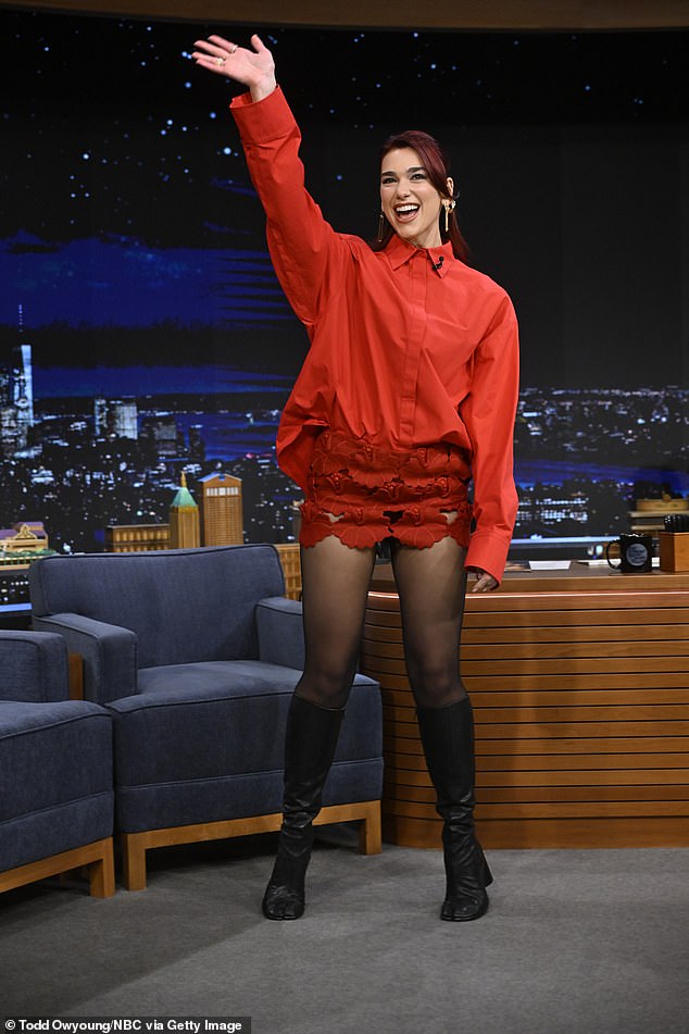 Дуа носила красную рубашку с длинными рукавами и такую ​​же юбку, а также черные ботинки.