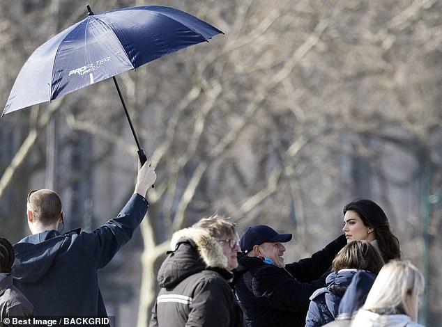 Поняв намек, пришел рабочий с большим зонтиком, который он держал под углом перед Кендалл и режиссером-перфекционистом.