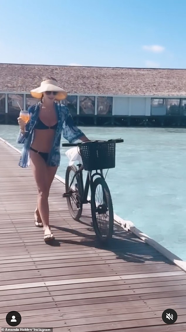 Аманда также носила синее кимоно с тропическим узором и шлепанцы, катаясь на велосипеде рядом с ней на фоне потрясающего фона.