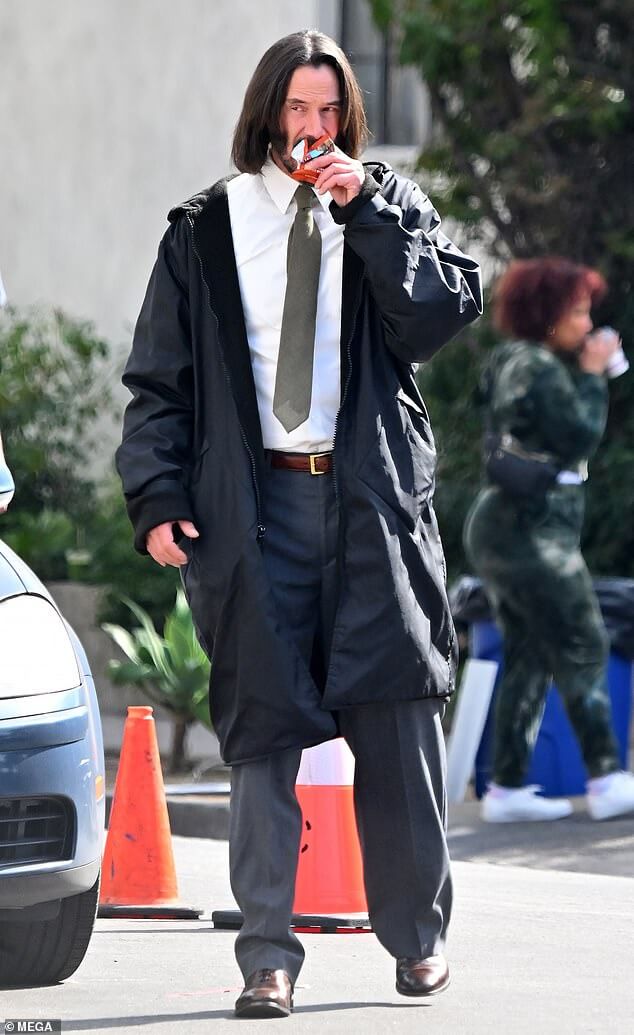 Киану Ривз жует свой любимый энергетический батончик в рубашке и галстуке на съемках своего фильма «Удача» в Лос-Анджелесе.