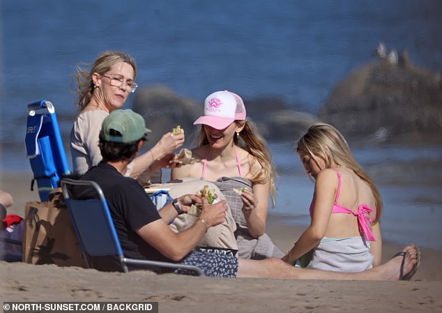 Семья, похоже, была в восторге, греясь на солнце и наслаждаясь едой на пляже.