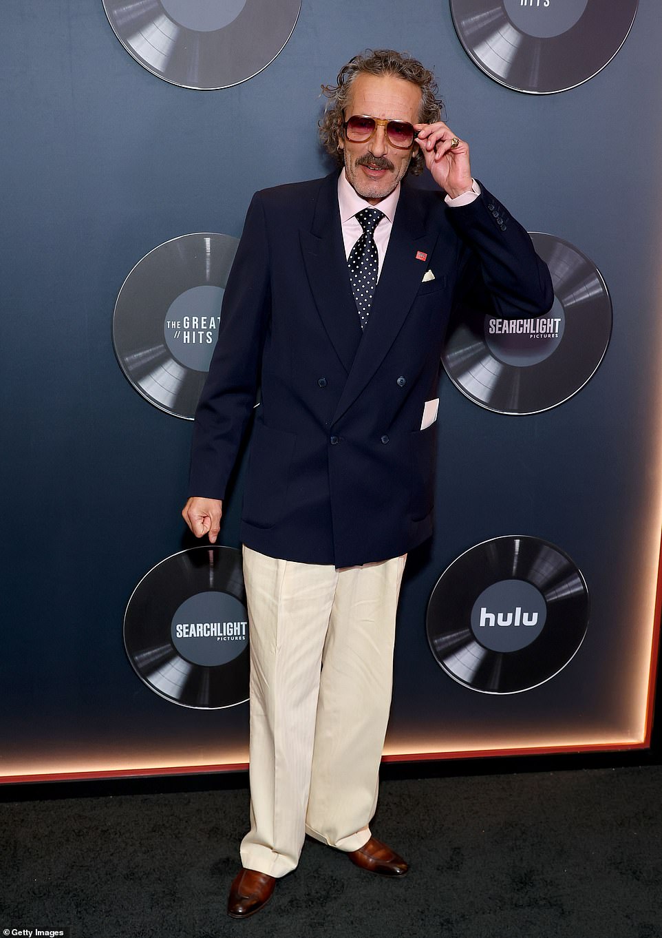 «Диджей Харви» Бассетт, который играет Тома и был музыкальным консультантом, носил оттенки омбре со своим двубортным темно-синим пиджаком, соответствующим галстуком в горошек, кремовыми льняными брюками и коричневыми оксфордами.
