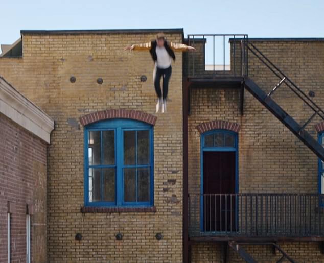 Смельчак Трой прыгает с крыши здания в надувную лодку внизу.