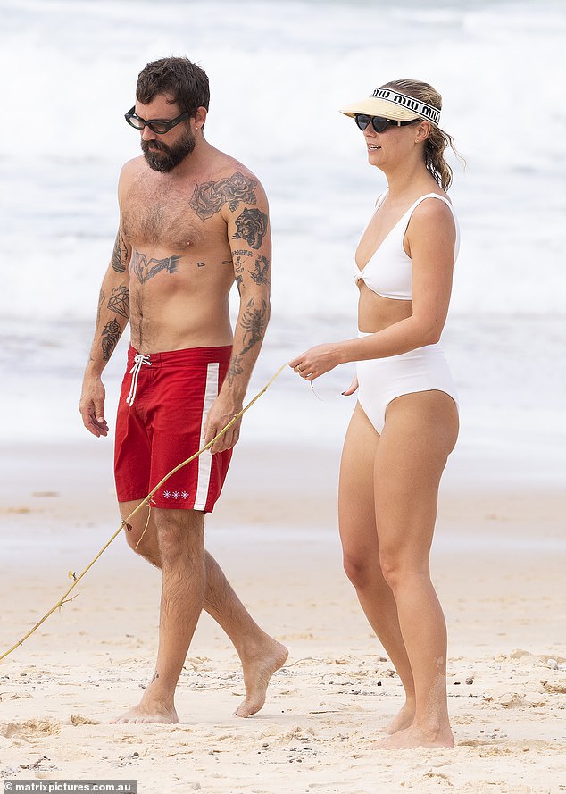 В пятницу недавно одинокая блондинка, 32 года, вся улыбалась, выходя на пляж в Нусе, Квинсленд, со своим новым приятелем-мужчиной, модельером Мэтти Бурисом (слева).