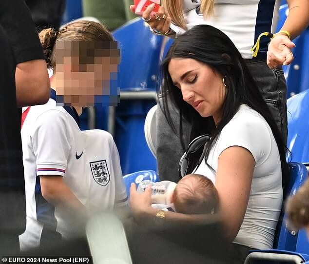 Энни Килнер кормит из бутылочки младенца Резона, подбадривая Англию с трибун после того, как она «полетела на частном самолете в Германию»… как утверждают друзья, она «окружена любовью» от коллег по WAGS